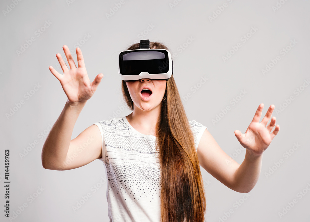 Woman with virtual reality goggles. Studio shot, gray background Woman with virtual reality goggles. Studio shot, gray background