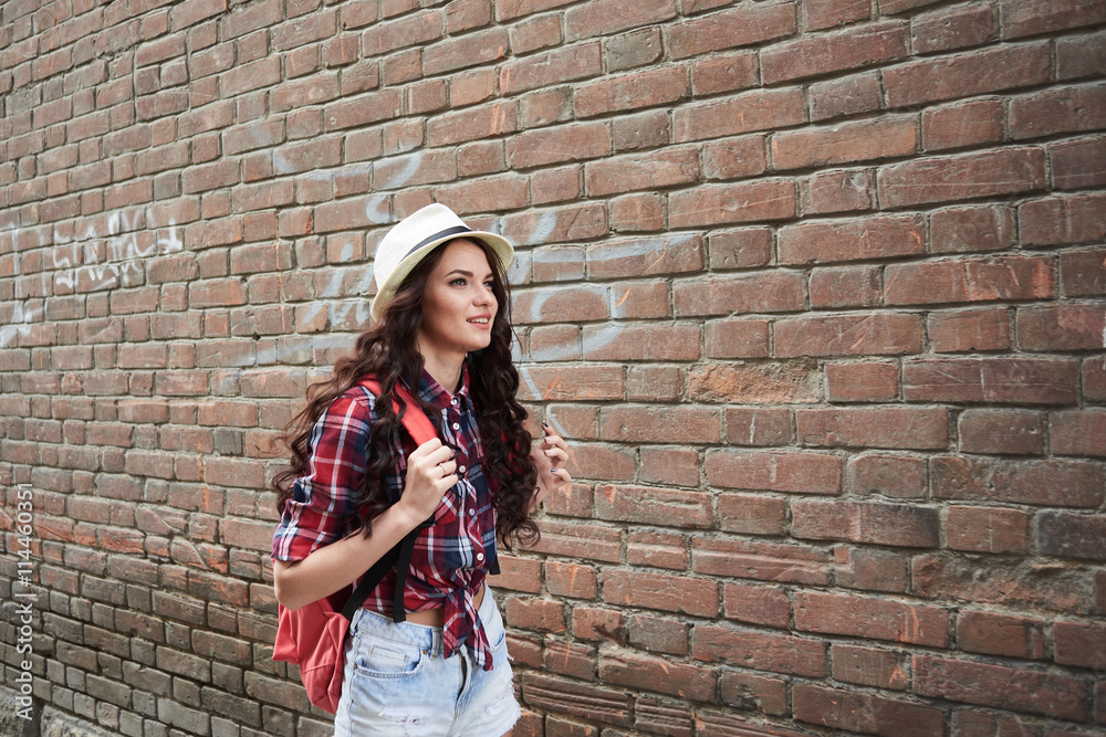 Portrait of a girl tourist in a hat on a background of red brick building Portrait of a girl tourist in a hat on a background of red brick building