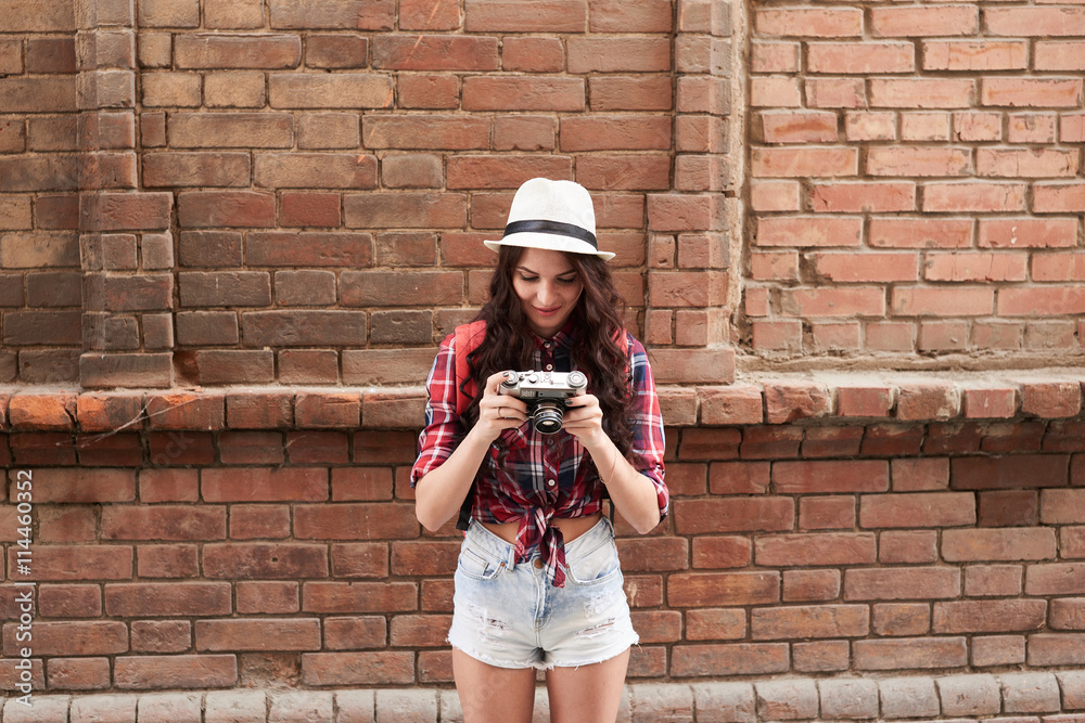 Portrait of a girl tourist in a hat holding and looking at the camera on the background wall red brick building Portrait of a girl tourist in a hat holding and looking at the camera on the background wall red brick building