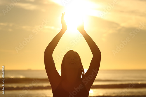 Woman holding sun at sunset