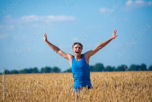 Fototapet Young happy man in a wheat field.