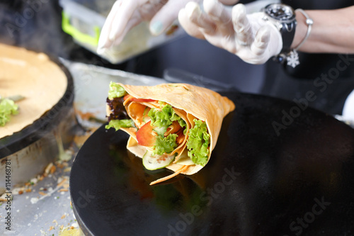 Obraz na plátně Vendor making crepe with vegetables outdoors