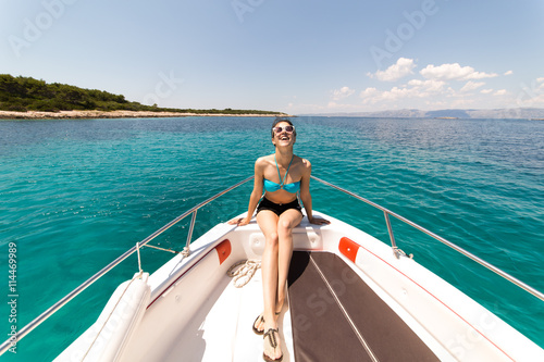 Beautiful woman standing on shipboard and getting ready to sail away to an open sea. Woman on her private boat on a sunny summer day. Luxury vacation at sea. Getting fascinated by sea life.Honeymoon