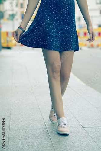 girl legs dressed in a short dress and shoes. Toned photo