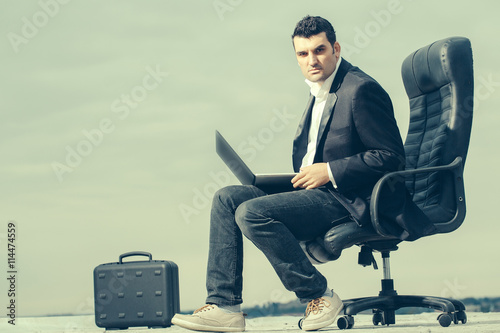 businessman with laptop on chair outdoor