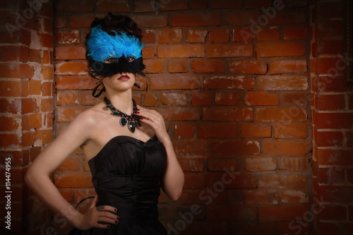Sensual gothic woman in a long gorgeous black dress and mask