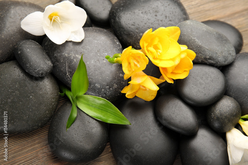 Beautiful spa composition with stones and freesia on wooden background