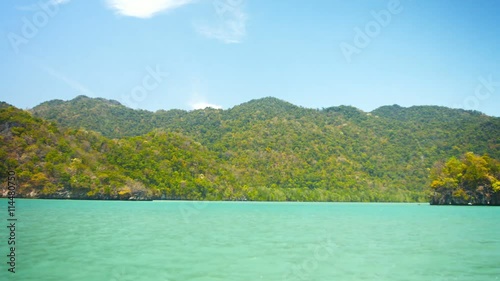 Wallpaper Mural FullHD video - Cruising by a forested tropical island wilderness on a sunny day in timelapse, with a tiny, solitary island in the foreground. Torontodigital.ca
