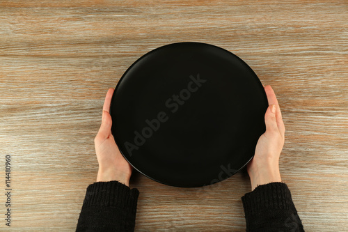 Woman hands holding empty plate, top view