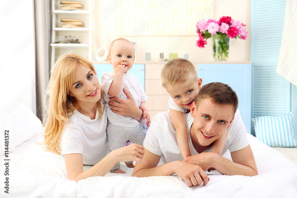 Happy family on white bed in bedroom Happy family on white bed in bedroom
