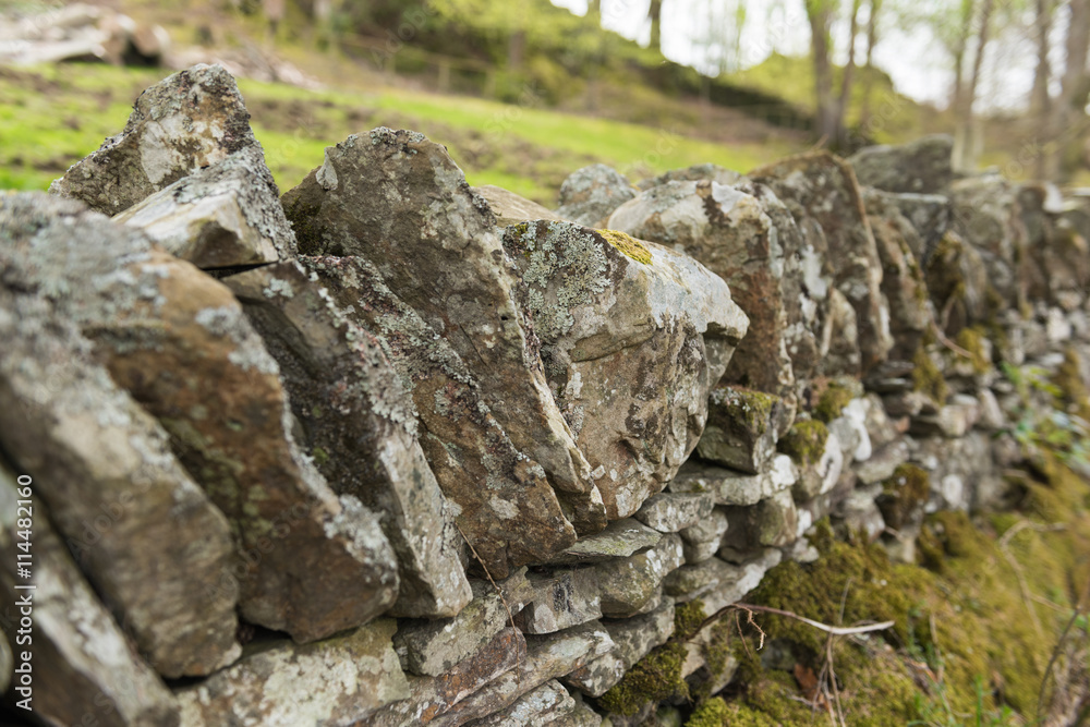 Old dry stone wall in the english countryside vanishing into the distance, with shallow depth of field