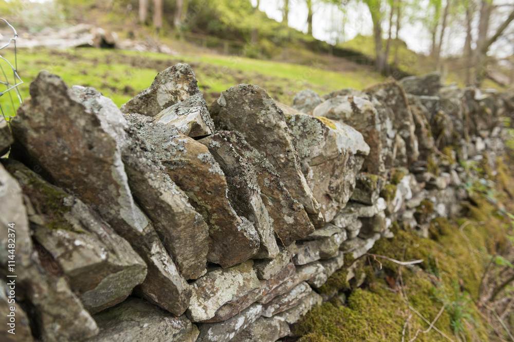 Old dry stone wall in the english countryside vanishing into the distance, with shallow depth of field