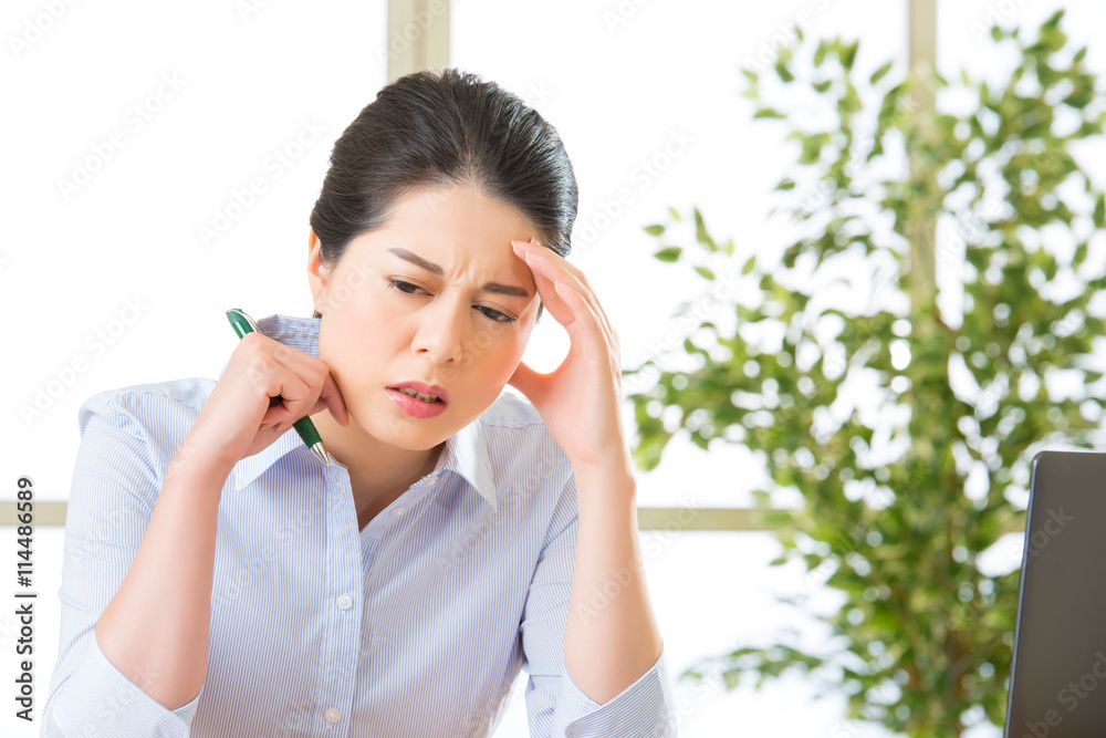 Young asian business woman writing with headache Young asian business woman writing with headache