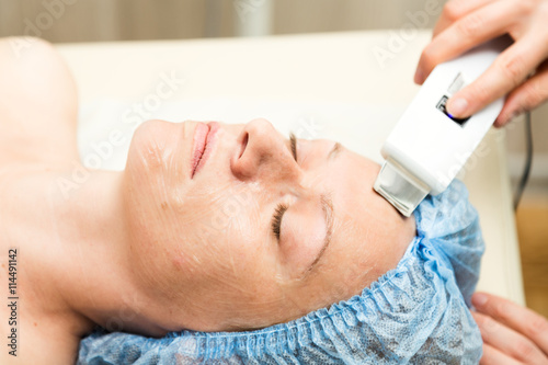 Young woman lying down in a spa salon and having a Ultrasonic face cleaning. The cosmetic procedures for the face. Beauty treatments in the spa salon. Facial Skin Care