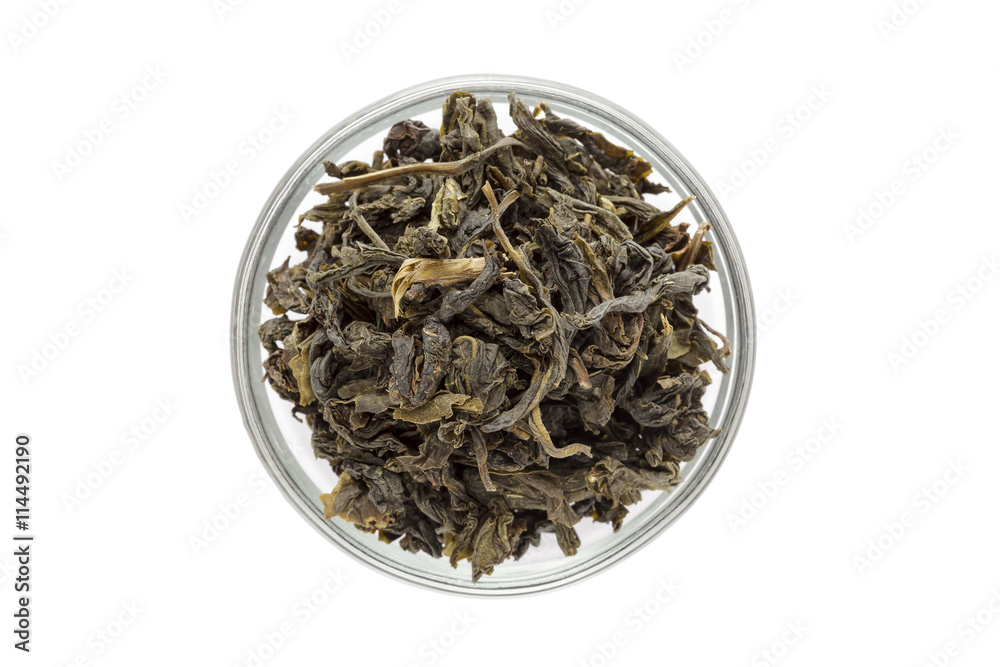 Fototapeta premium Organic Green Tea (Camellia sinensis) dried long leaves in glass bowl isolated on white background. Macro close up. Top view.