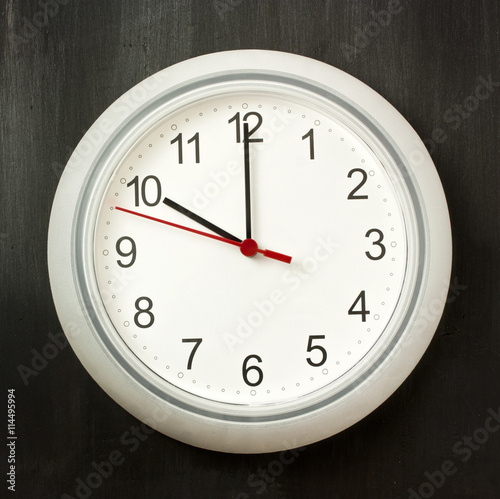 Photo of typical white office clock on dark background