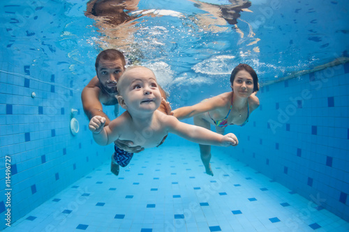 Photography Happy full family - mother, father, baby son learn to swim, dive underwater with fun in pool to keep fit