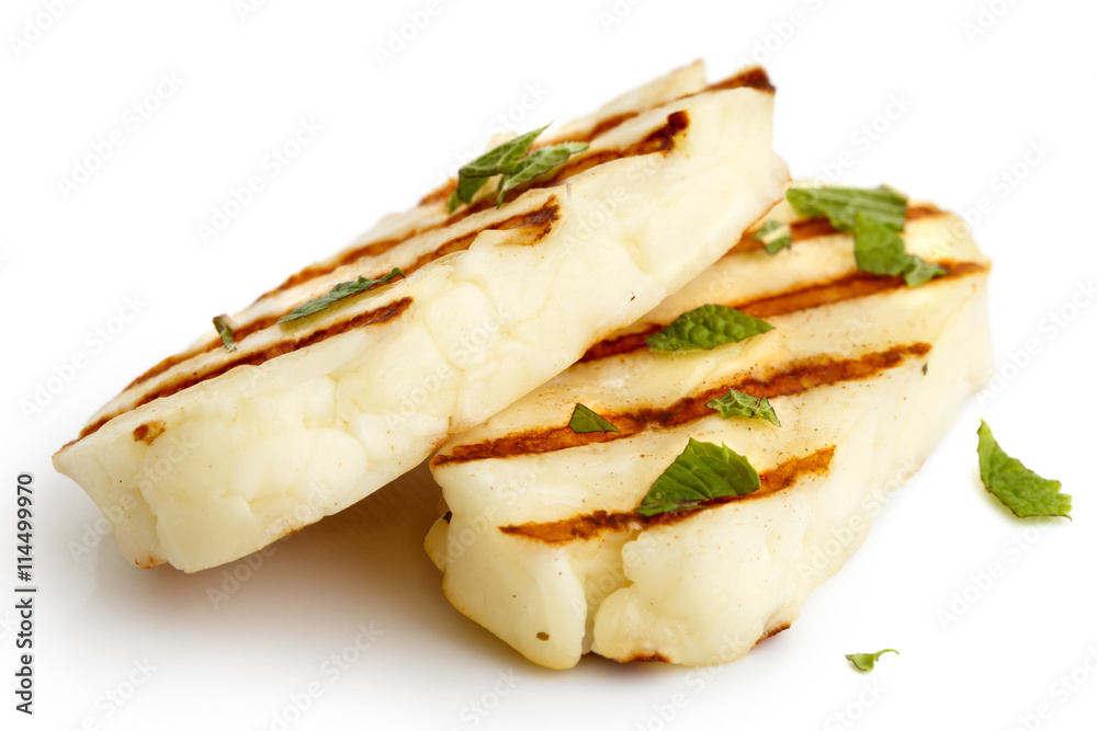 Two grilled slices of halloumi cheese isolated on white in perspective. With grill marks and mint. Two grilled slices of halloumi cheese isolated on white in perspective. With grill marks and mint.