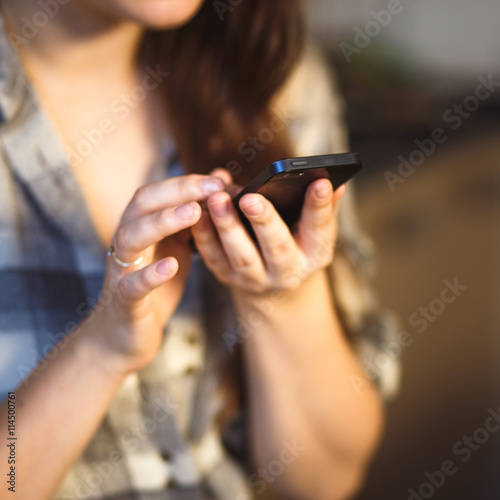 Pretty young brunette woman sitting in a kitchen and write on her mobile phone