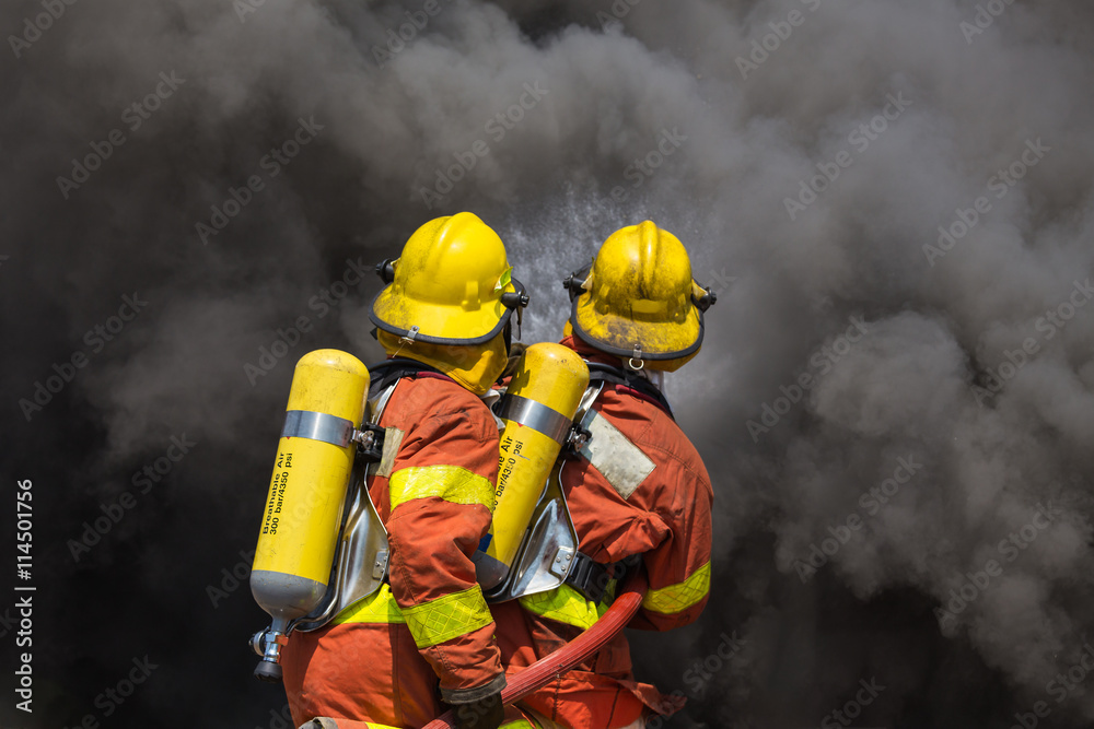 Fototapeta premium two firefighter in fire fighting suit spraying water to fire and