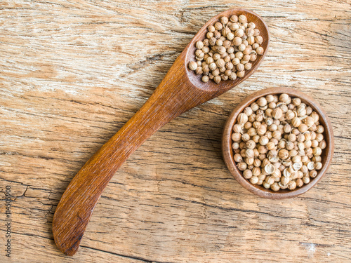 Dried coriander seeds on wood background