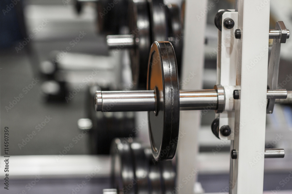Weightlifting training device at gym close-up. Exercise mashine with barbell. Weight plate on barbell at gym Weightlifting training device at gym close-up. Exercise mashine with barbell. Weight plate on barbell at gym