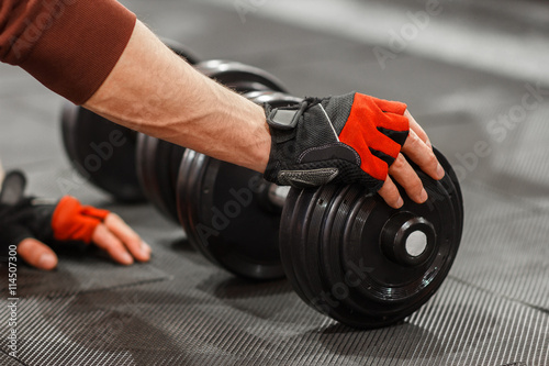 Fotografi Male hand touching dumbbell on gym floor closeup