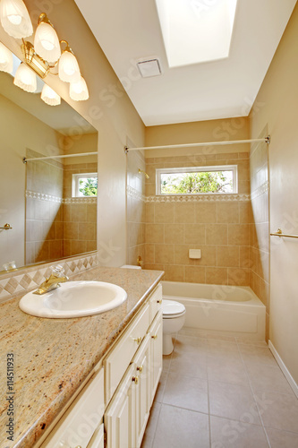 Light bathroom interior with wooden cabinets and tile floor.