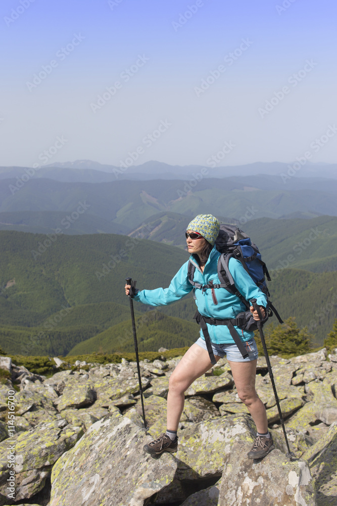 Girl with a backpack in a mountain hike in the summer.