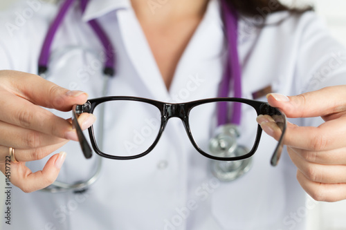 Fototapeta Naklejka Na Ścianę i Meble -  Female oculist doctor hands giving pair of glasses. Good vision