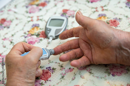 Senior woman is checking her sugar level with glucometer. In 2013 it was estimated that over 382 million people throughout the world had diabetes. photo