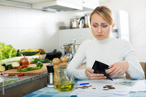 Broke woman with money and bills in kitchen