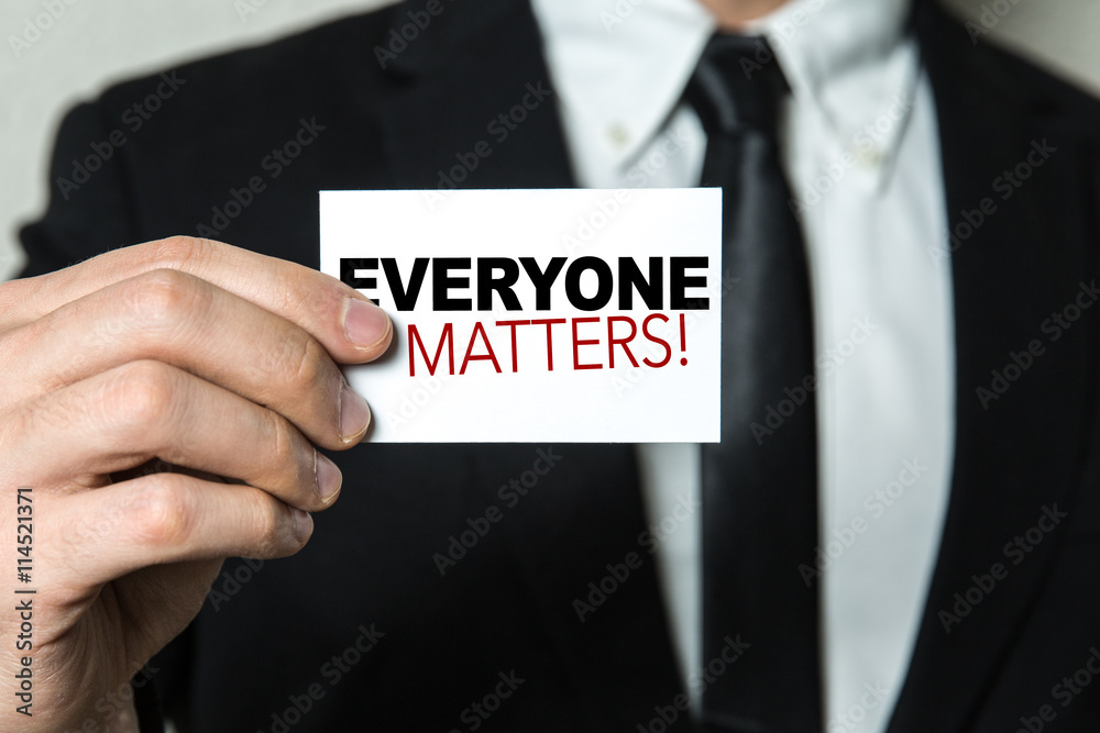 Business man holding a card with the text: Everyone Matters!
