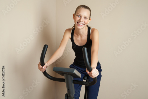 Smiling teen girl cycling at home