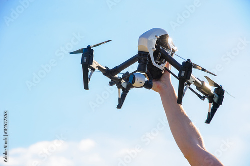 Drone with camera in man hand/Drone with a video camera in the hands of men against the sky