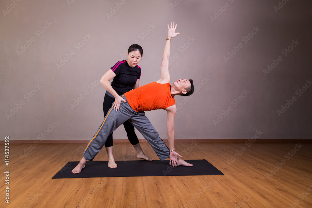 Yoga instructor guiding student perform triangle pose or Trikonasana