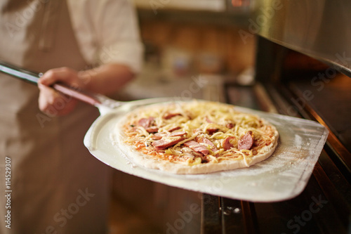 Putting pizza into oven