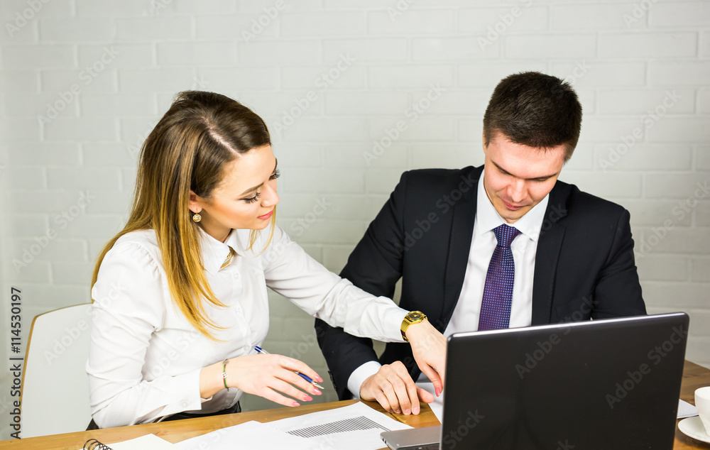 Two entrepreneurs sitting together working in an office desk comparing documents. Two entrepreneurs sitting together working in an office desk comparing documents.
