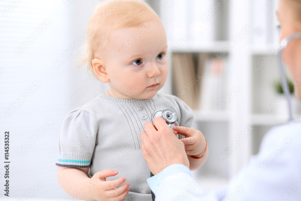 Pediatrician is taking care of baby in hospital. Little girl is being examine by doctor with stethoscope. Health care, insurance and help concept. Pediatrician is taking care of baby in hospital. Little girl is being examine by doctor with stethoscope. Health care, insurance and help concept.