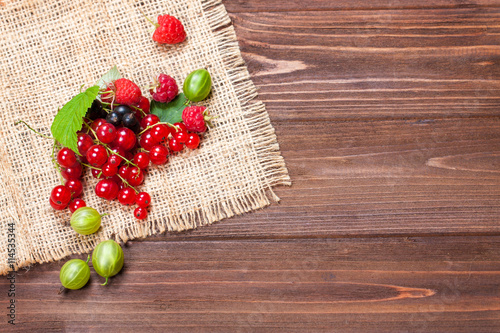 A mixture of ripe berries on a wooden table. Berries on a napkin, top view, empty space for text. Beautiful summer background