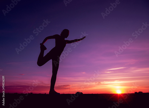 Young girl yoga on the roof. Silhouette