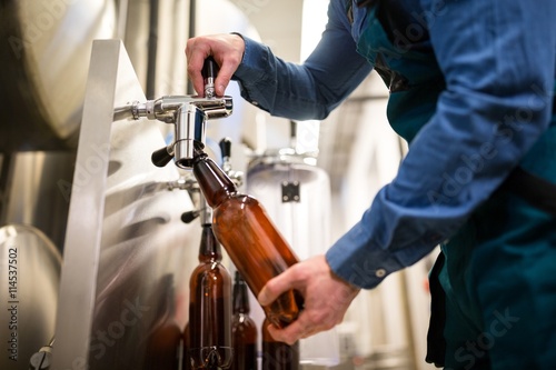 Tableau sur toile Brewer filling beer in bottle