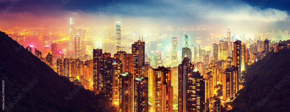 Fototapeta premium Panoramic view oover Victoria Harbor in Hong Kong, China, by night. Colorful travel background with illuminated skyscrapers seen from Victoria Peak.