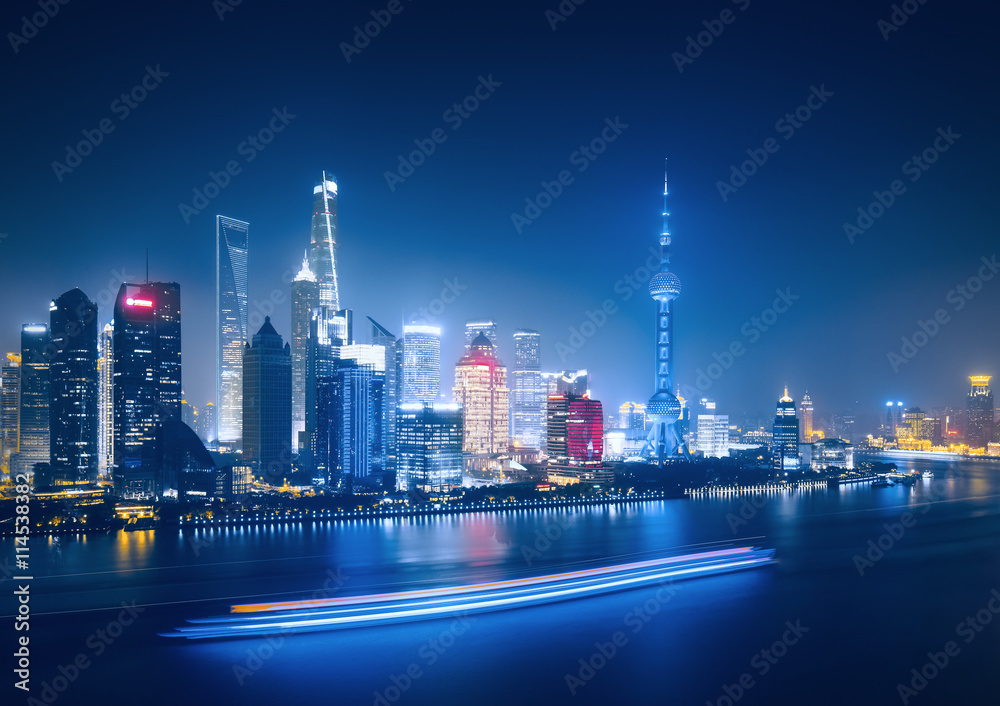 Big modern illuminated city by night. Shanghai, China. Nighttime skyline with skyscrapers and the Hunapu river.