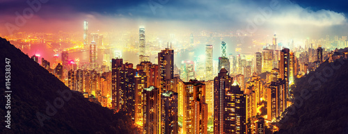 Panoramic view oover Victoria Harbor in Hong Kong, China, by night. Colorful travel background with illuminated skyscrapers seen from Victoria Peak. photo