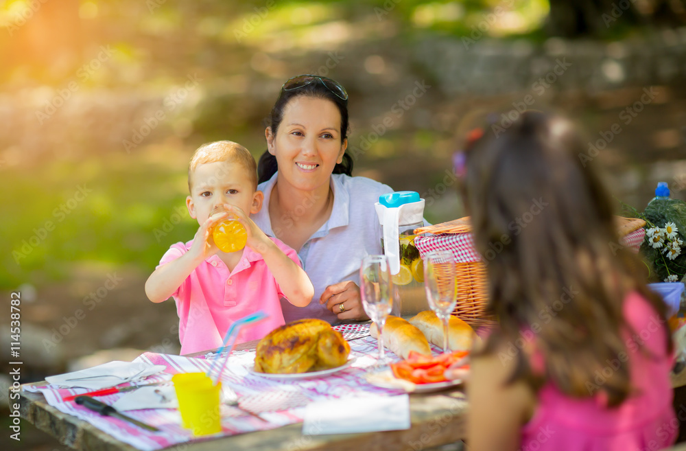 Mother with children enjoying on picnic sitting on a bench Mother with children enjoying on picnic sitting on a bench