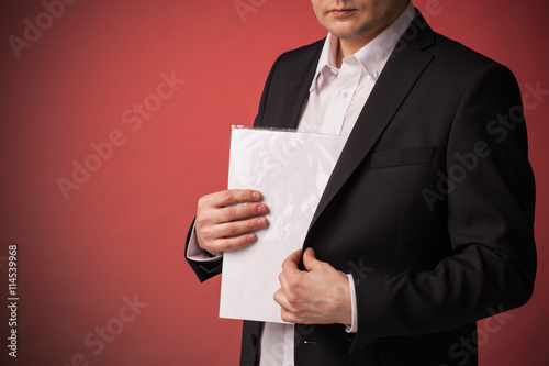 businessman in a black jacket and white shirt hides contract on red background