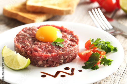 Beef tartare with egg yolk on a grey wooden table