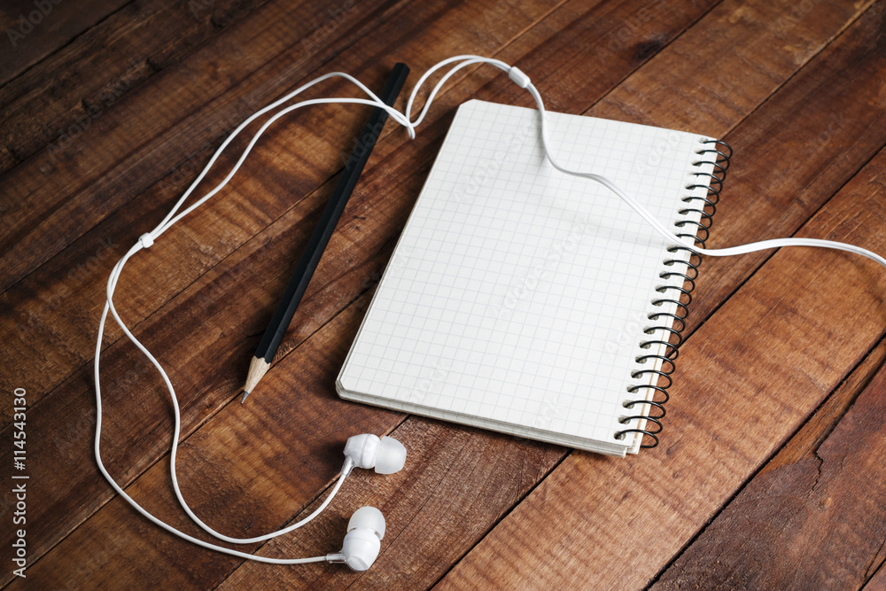 Blank notepad, pencil and headphones on wooden table background. Blank paperwork template for design portfolios. Responsive design template. Mock-up for your design. Blank notepad, pencil and headphones on wooden table background. Blank paperwork template for design portfolios. Responsive design template. Mock-up for your design.
