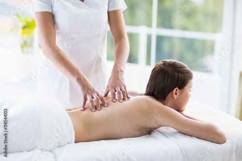 Midsection of masseuse giving massage to woman